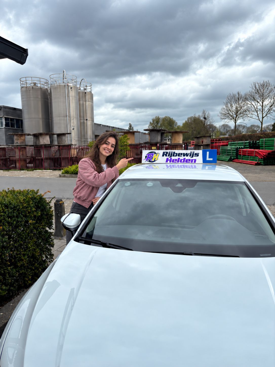 Geslaagd voor auto rijbewijs bij beste rijschool specialist Dordrecht Rijbewijs Helden Geslaagde leerling naast de lesauto van Rijbewijs Helden in Dordrecht