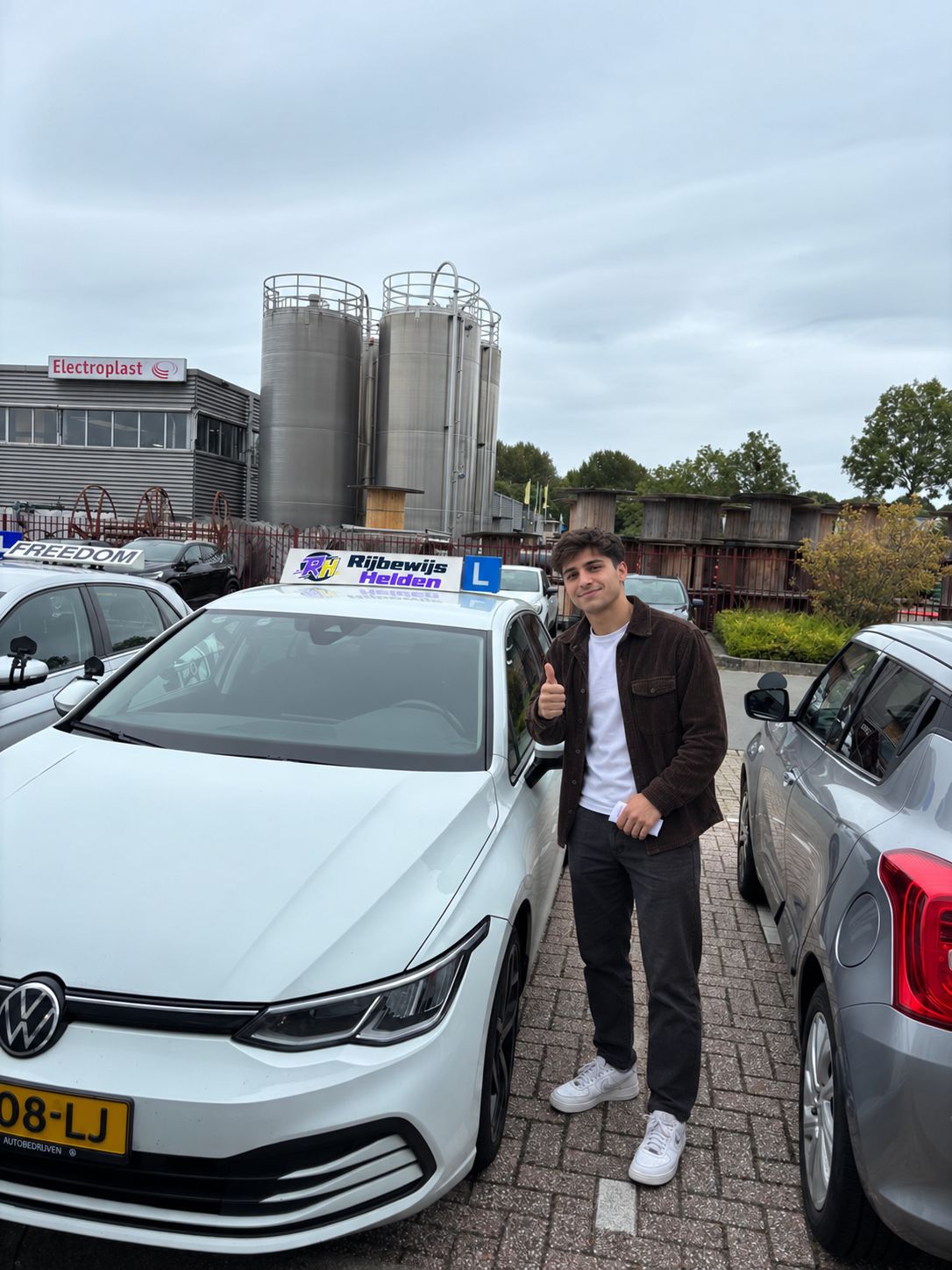 Passed with Rijbewijs Helden Student who passed, next to the Rijbewijs Helden driving school car in Dordrecht