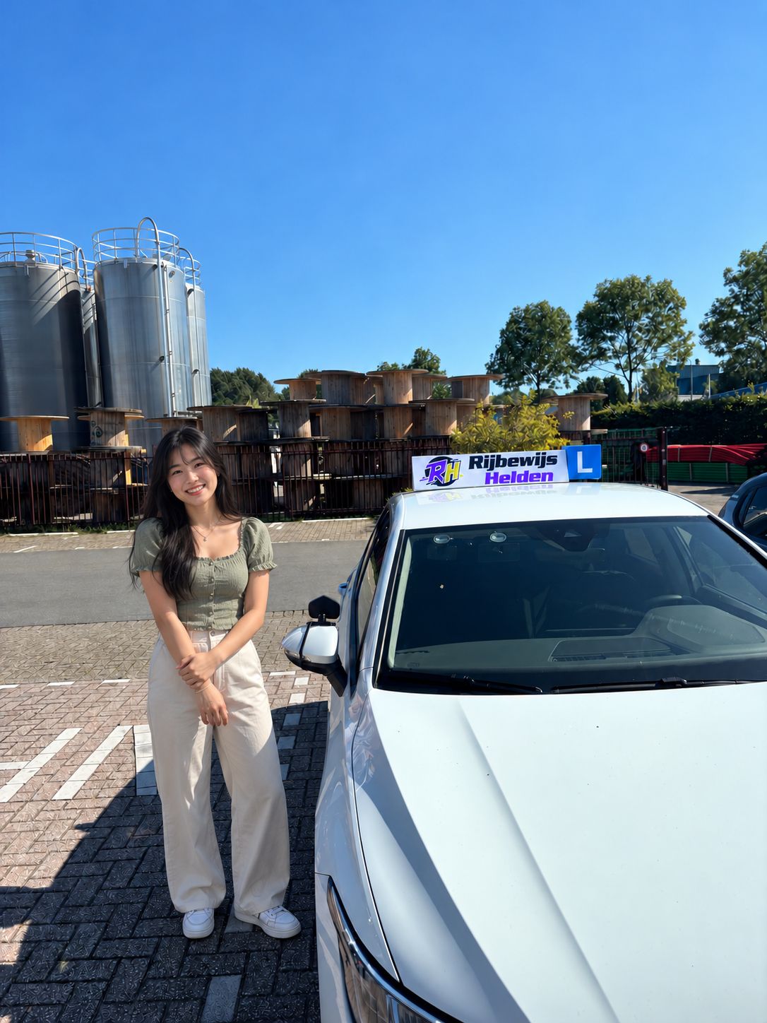 Passed with Rijbewijs Helden Student who passed, next to the Rijbewijs Helden driving school car in Dordrecht